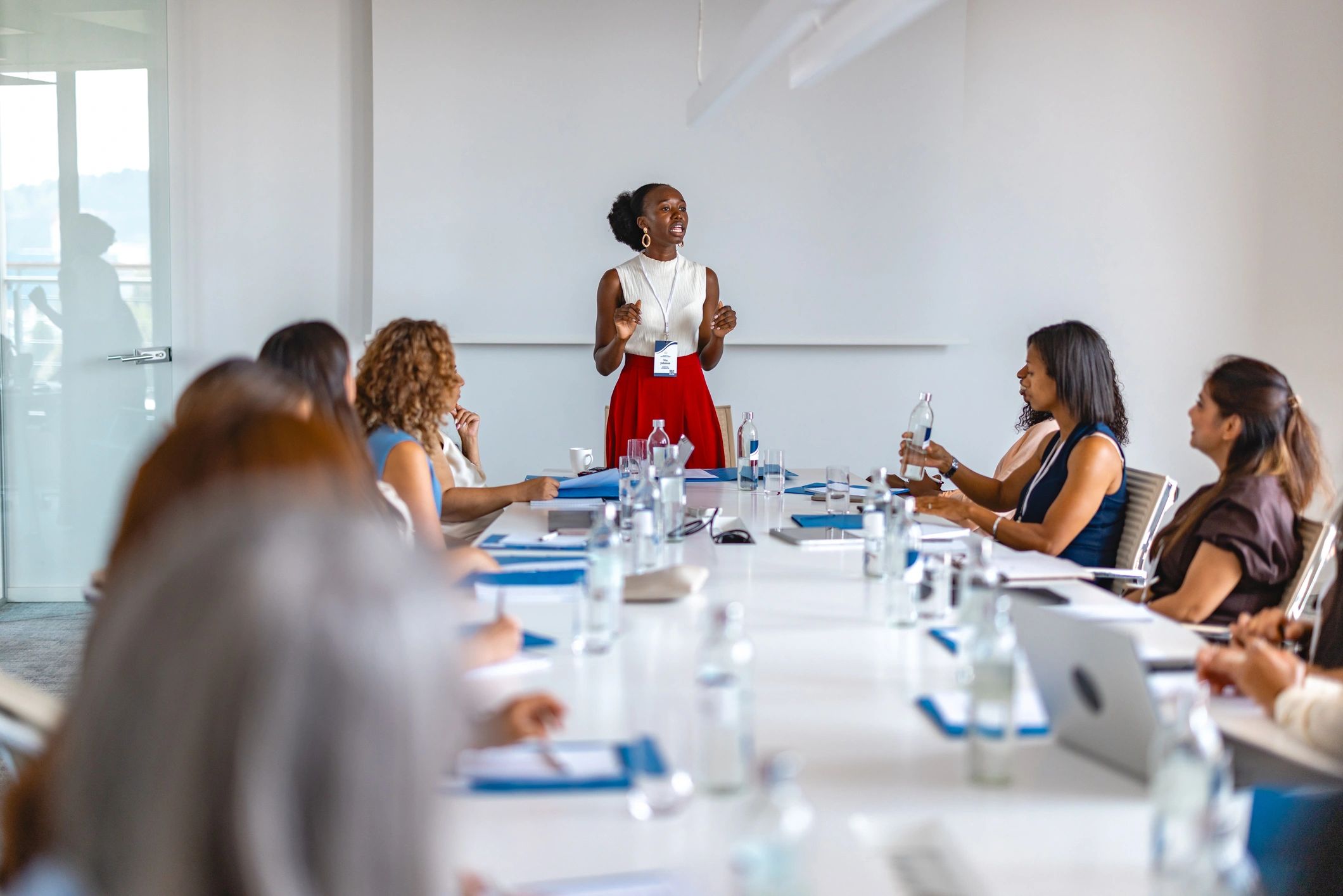 Woman leading a workshop discussion with participants seated around a table